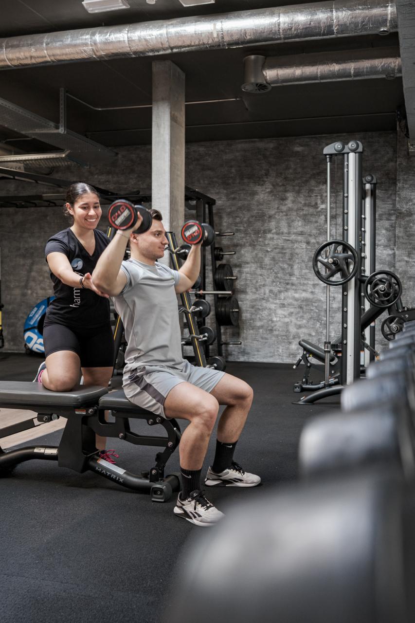 Coach accompagnant un membre sur le plateau fitness Harmony